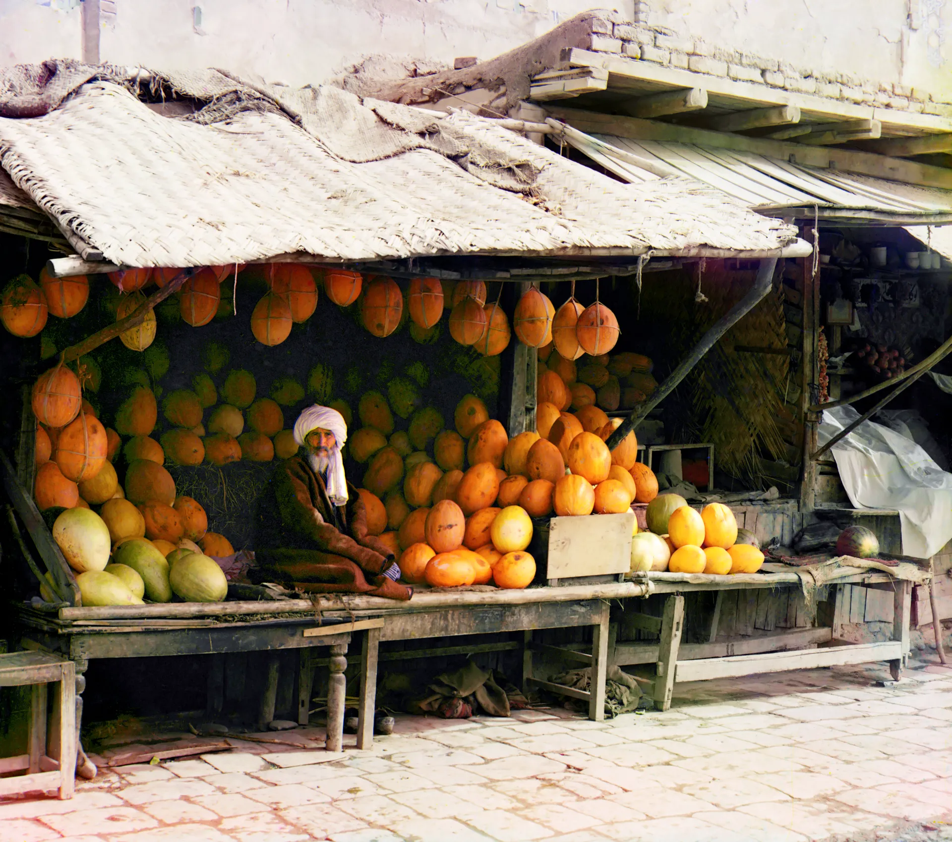 A melon vendor at his stall in a Samarkand market, photographed in colour by Sergey Prokudin-Gorsky in the years when the Jadids were opening their first schools.